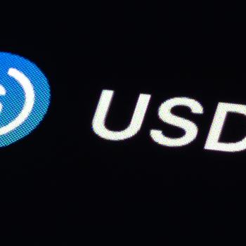 The stablecoin USD Coin (USDC) logo is displayed on a screen. 
