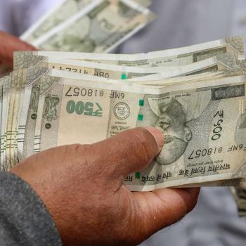 An employee counts Indian Rupee currency at a market in Kashmir. May 2026. 
