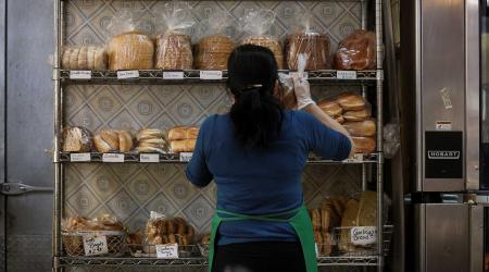 A baker stocks shelfs with bread at a market during high inflation. Washington, D.C. 