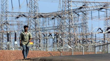 A man walks past electrical towers at a power plant in Dabhol, India. 
