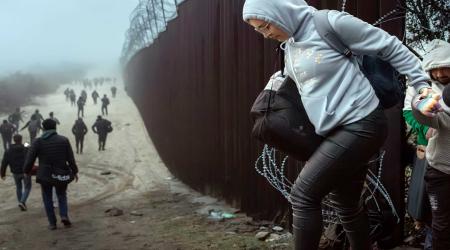 Migrants cross through a gap in the US-Mexico border fence in Jacumba Hot Springs, California. Picture taken December 22, 2023. 