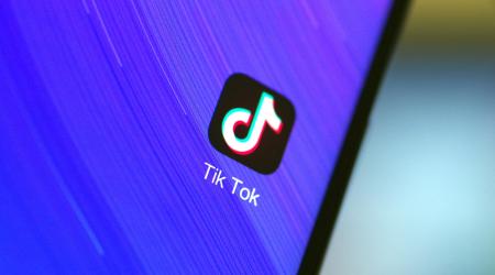 Tik Tok logo is displayed on a cell phone. 