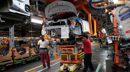 Assembly workers connect a battery pack underneath a partially assembled EV vehicle in Lake Orion, Michigan, U.S. 