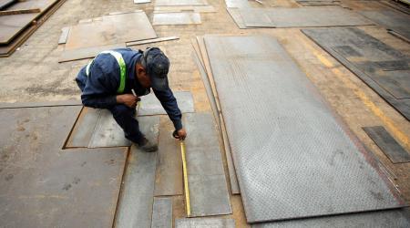 An employee measures steel plates at a steel factory in Ciudad Juarez, Mexico. 