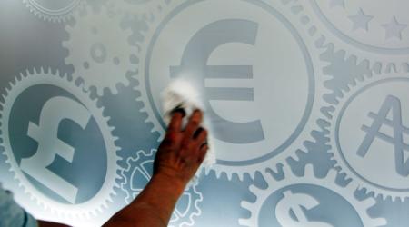 A man cleans a board showing different monetary symbols, in Madrid, Spain. 