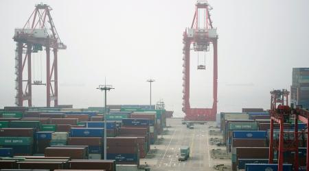 Trucks travel past containers at the Yangshan Deep Water Port in Shanghai, China. January 13, 2022.