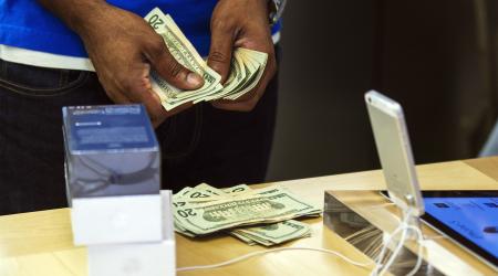 An employee counts cash after selling a customer three cell phones in New York City.