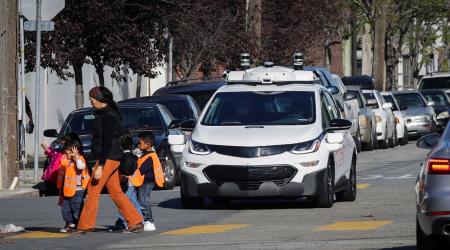 Children pass by a self-driving EV car, in San Francisco, California. 