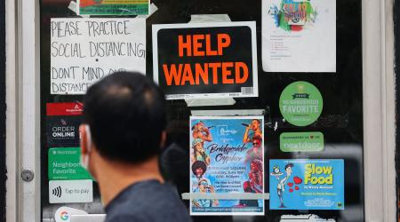 A pedestrian passes a "Help Wanted" sign in the door of a hardware store in Cambridge, Massachusetts on July 8, 2022. 