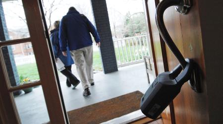 A realtor's lock box hangs on a door as prospective buyers depart a house for sale in Alexandria, Virginia. 