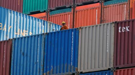 A worker sits on a ship carrying containers at a port in India. 