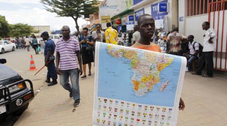 A vendor holds a map of Africa along the streets of Bujumbura, Burundi. 