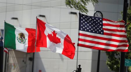 Flags of the US, Canada, and Mexico fly next to each other in Detroit, Michigan. 