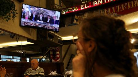 People watch Argentina’s President Javier Milei give a speech as he addresses people on national TV, on the day Argentina’s government reached an agreement with the International Monetary Fund. Buenos Aires, Argentina, April 11, 2025. 