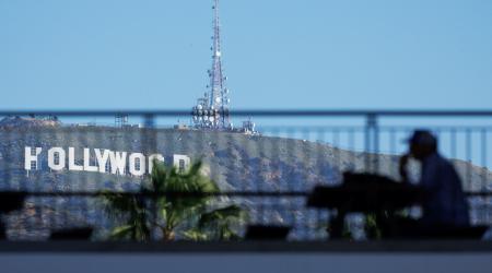 The iconic Hollywood sign is shown behind a person sitting along Hollywood Blvd. Film production in Hollywood has been declining in recent years. February 25, 2025. 
