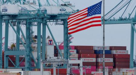 A U.S. flag flutters near shipping containers as a ship is unloaded at the Port of Los Angeles, in San Pedro, California, U.S., May 1, 2025. 