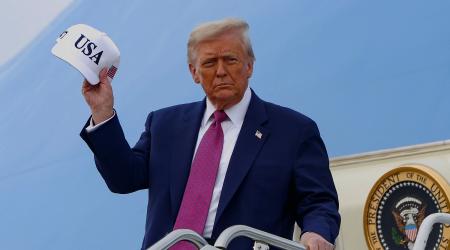 President Donald Trump holds a USA hat as he disembarks Air Force One. Picture taken on June 10, 2025. 