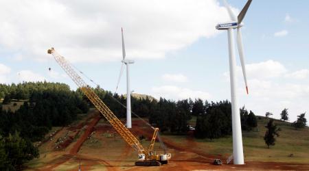A crane is used to carry out the construction work of wind turbines near a power plant in Africa. 