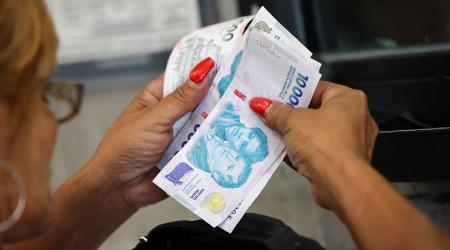 A customer counts Argentine peso bills in Buenos Aires, Argentina. Picture taken on January 13, 2025. 