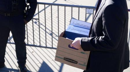 A person carries a box with documents as Supreme Court justices are set to hear oral arguments in the consolidated cases of Learning Resources, Inc. v. Trump and Trump v. V.O.S. Selections, at the US Supreme Court in Washington, DC. Picture taken on November 5, 2025. 