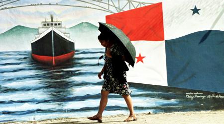 A woman passes by a mural depicting the Panama Canal, in Panama City. 