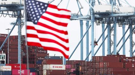 A US flag is pictured in front of containers at a port in California. 