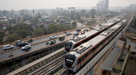 Metro trains move past commuters near the Sabarmati Metro station in Ahmedabad, India. Picture taken on January 31, 2026. 