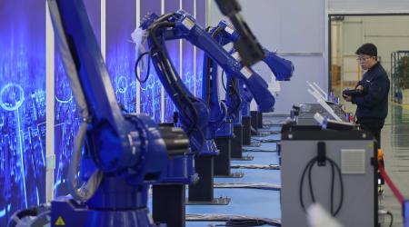 A technician works on robotic arms in a manufacturing plant in China. Photo taken on March 12, 2026.