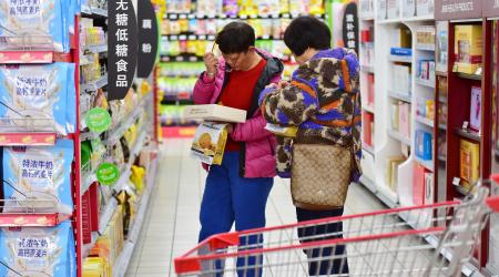 Two shoppers examine product pricing at a supermarket in China. Photo taken in December 2025. 