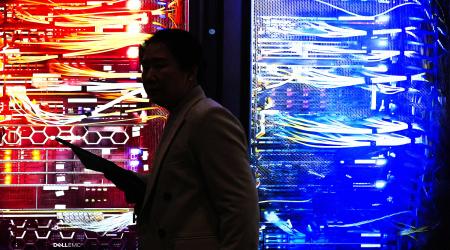 A person passes by a lit-up picture of a RAC AI server during the Mobile World Congress trade show in Barcelona, Spain. Photo taken on March 2, 2026. 