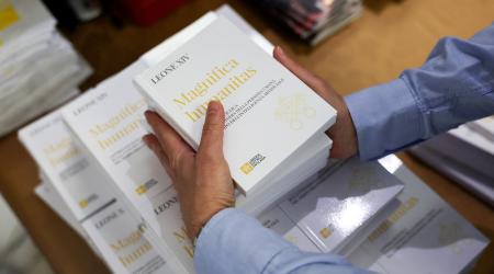 A worker places copies of Pope Leo XIV's first encyclical "Magnifica Humanitas" that focuses on the rise of AI. Photo taken at the Vatican on May 25, 2026. 