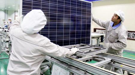 Workers check a solar panel at a manufacturing plant in Lianyungang city, China. 