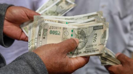 An employee counts Indian Rupee currency at a market in Kashmir. May 2026. 