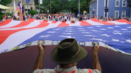 People help to stretch the American Flag out to begin the annual 4th of July celebration parade in Bristol, Rhode Island. July 2021. 