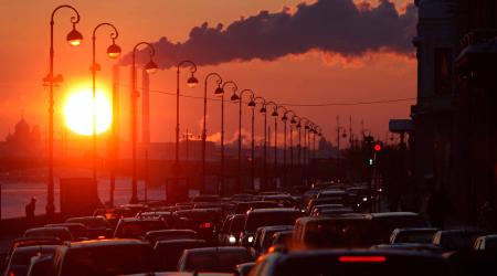 Pipes of a thermal power plant are seen during sunset, with cars stuck in a traffic jam in the foreground, February 15, 2011. 