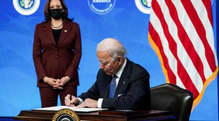U.S. President Joe Biden signs an executive order after speaking about his administration's plans to strengthen American manufacturing as Vice President Kamala Harris listens in the South Court Auditorium at the White House in Washington, U.S., January 25
