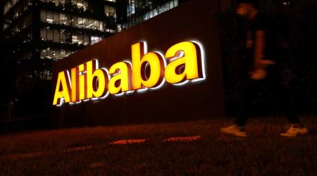 A man walks past a logo of Alibaba Group, August 9, 2021. 