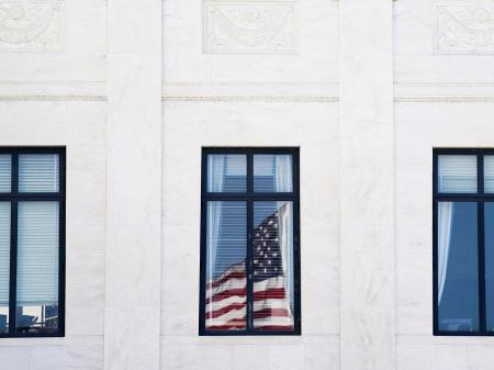 The US flag is reflected on a window of the US Supreme Court, as its justices are set to hear oral arguments on President Trump's bid to preserve sweeping tariffs after lower courts ruled that Trump overstepped his authority, in Washington, DC. Photo taken on November 5, 2025. 
