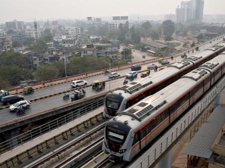 Metro trains move past commuters near the Sabarmati Metro station in Ahmedabad, India. Picture taken on January 31, 2026. 