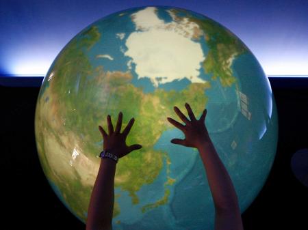 A visitor places her hands on a "Tangible Earth" at an exhibition pavilion on Japan's northern island of Hokkaido. July 6, 2008. 