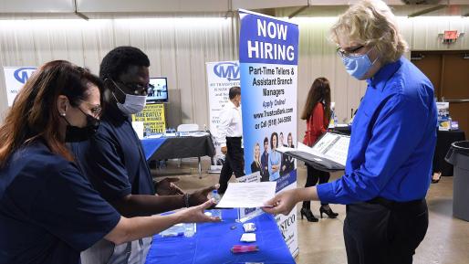 A man hands his resume to an employer at the 25th annual Central Florida Employment Council Job Fair at the Central Florida Fairgrounds. 