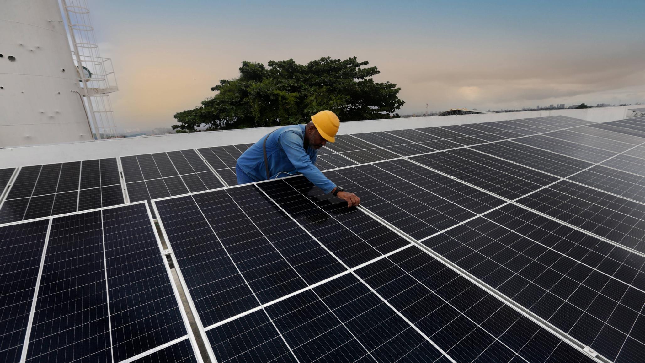 A worker installs solar energy panels on the roof of a public school in Brazil. June 2023. 