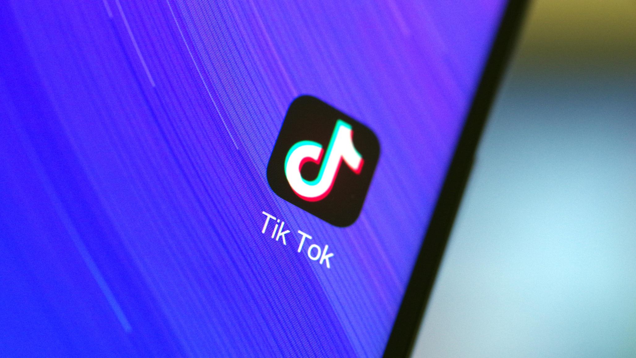 Tik Tok logo is displayed on a cell phone. 