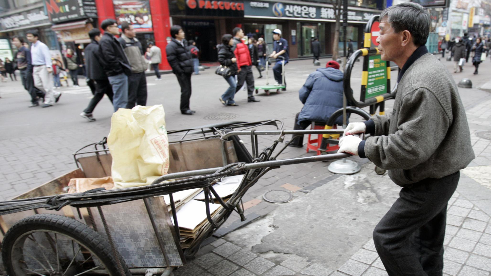 A man pushes a cart carrying paper at a shopping district in Seoul. 