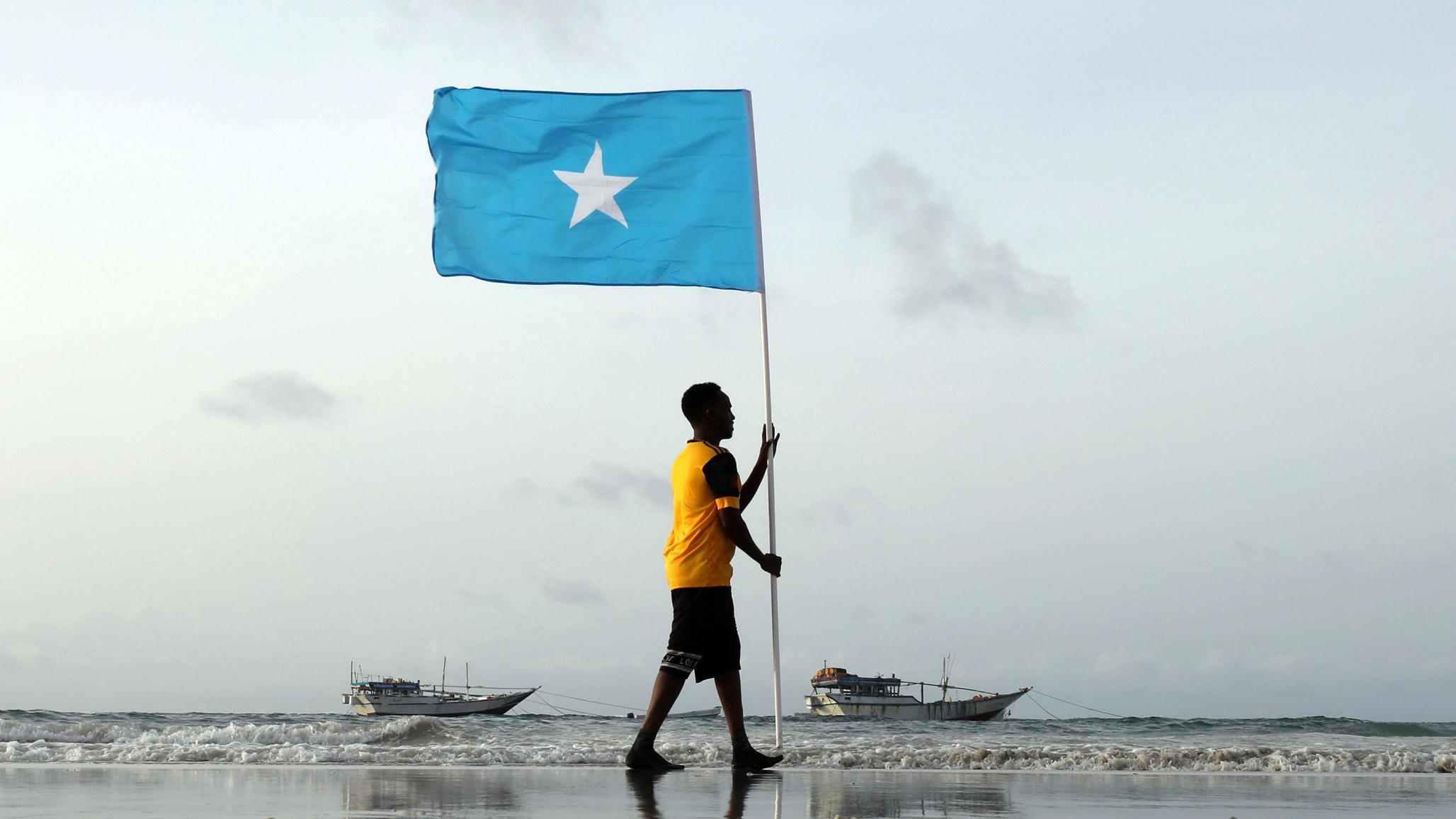 A Somali youth holds the national flag, at Lido beach, Mogadishu's Abdiaziz District, Somalia June 18, 2021. 