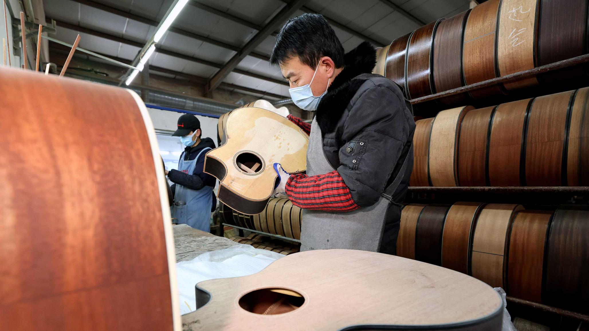 A worker inspects a guitar at a musical instrument manufacturing plant in China. Picture taken on January 4, 2024. 