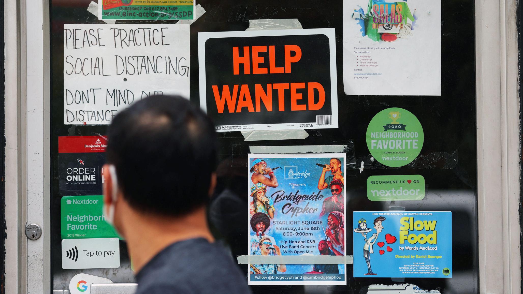 A pedestrian passes a "Help Wanted" sign in the door of a hardware store in Cambridge, Massachusetts on July 8, 2022. 
