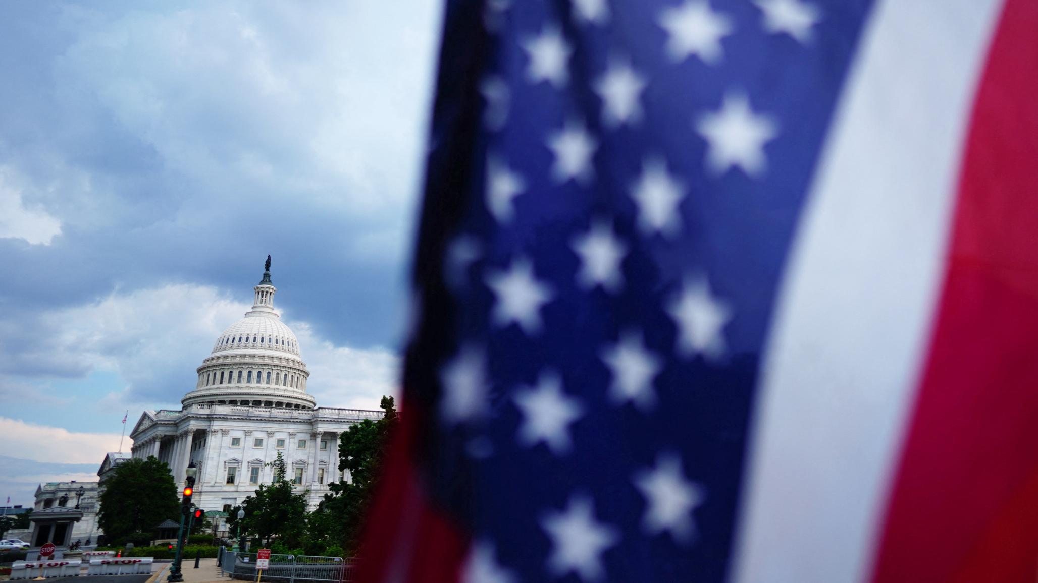 The US Capitol stands behind a US flag were Republican lawmakers worked to pass President Donald Trump’s sweeping spending and tax bill. Picture taken July 2025. 