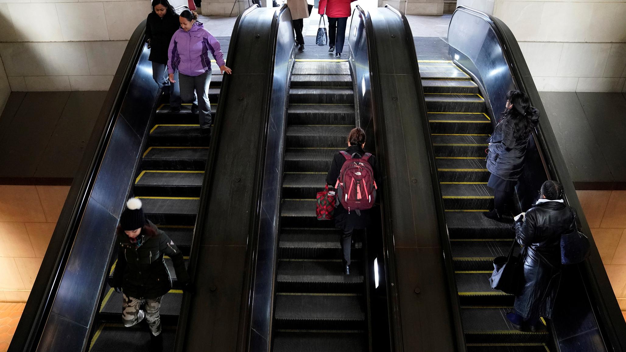 Commuters walk on the escalator at a metro station in Washington, DC. 