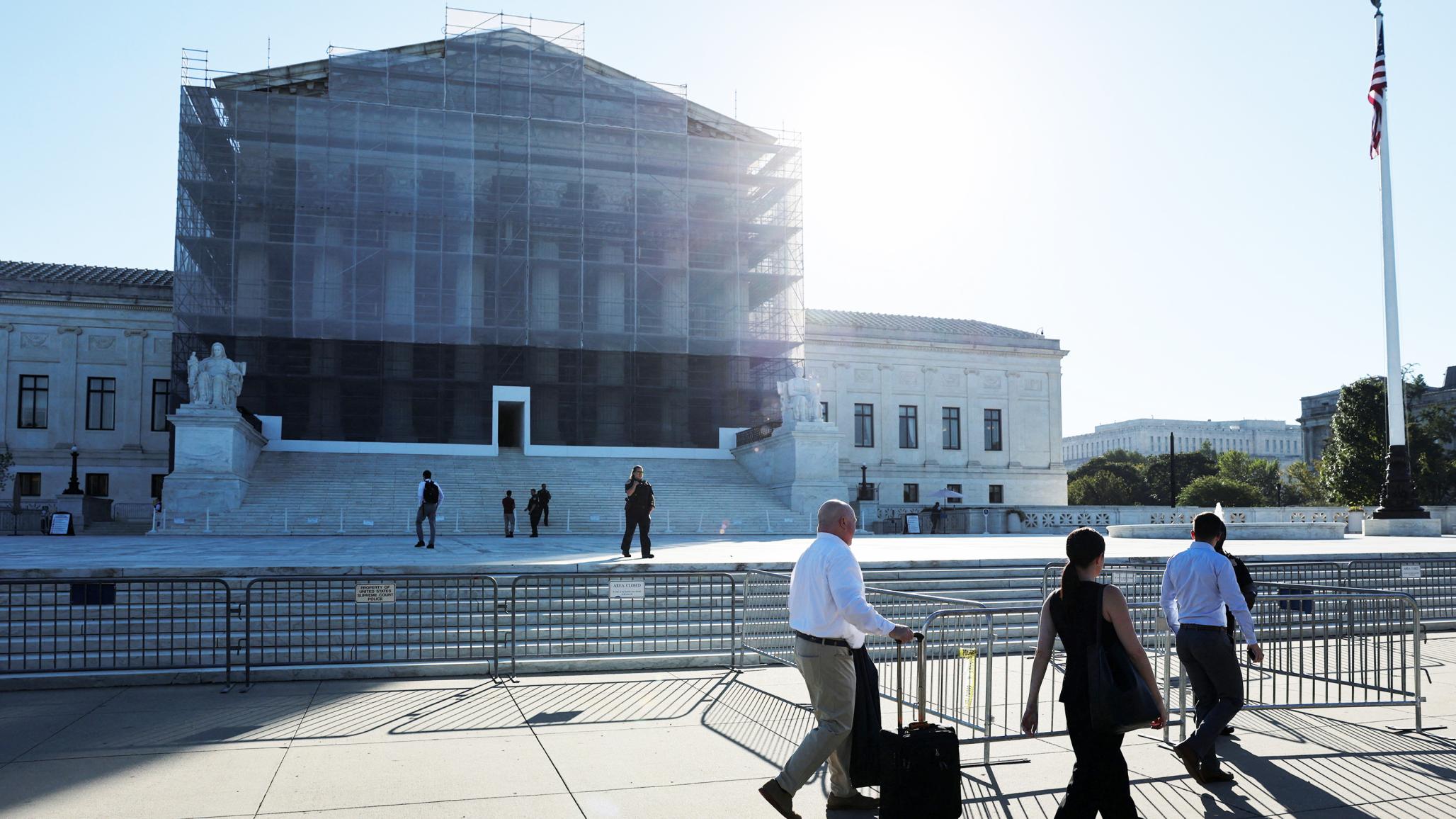 People walk past the US Supreme Court building, where oral arguments are scheduled for November 5, challenging President Trump's authority to impose certain tariffs using the International Emergency Economic Powers Act. Picture taken on October 6, 2025. 
